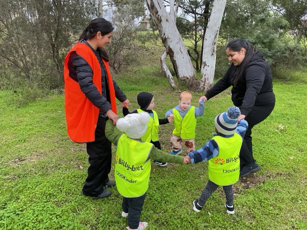 Two Billy-beet educators playing a ring game with children in the bush