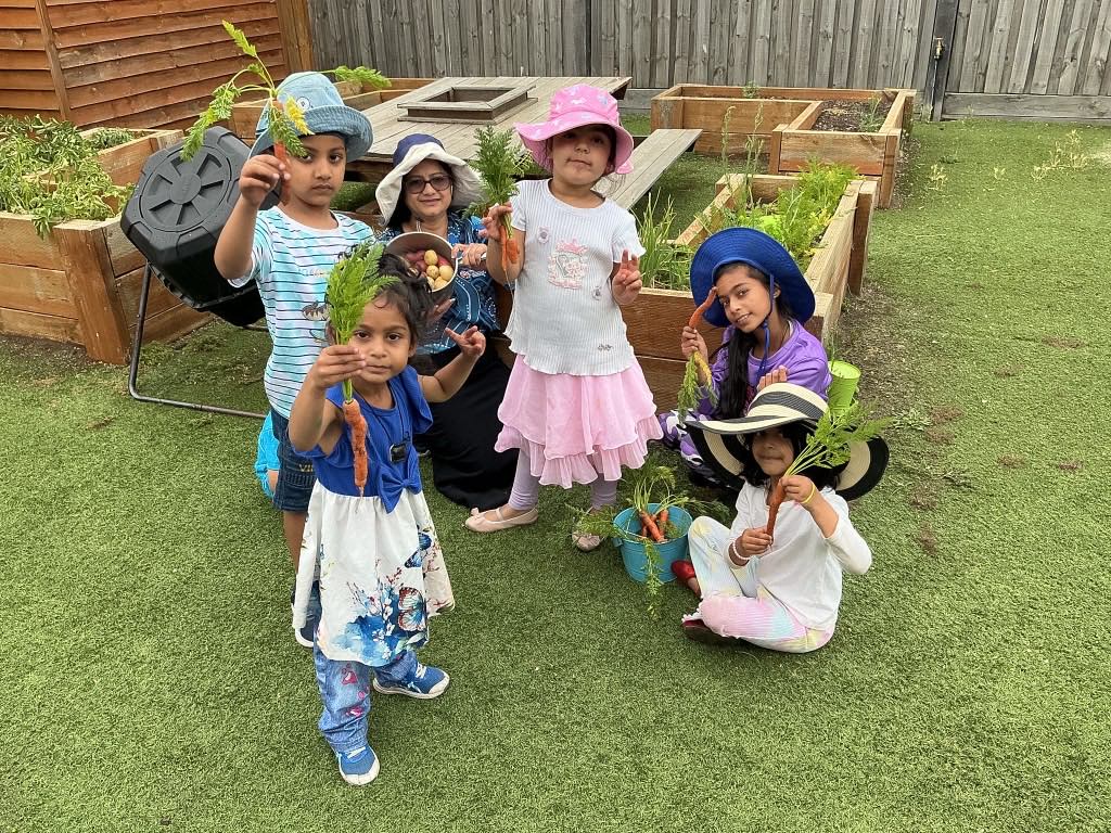Children proudly holding carrots they grew in the Billy-beet Melton garden beds