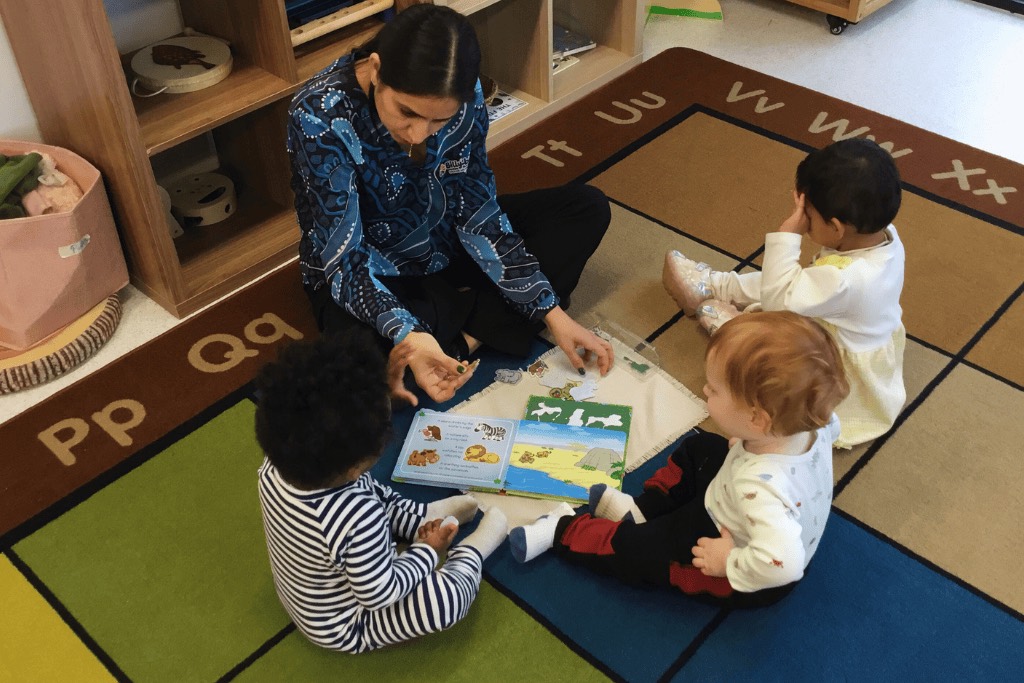 A Billy-beet educator reading with infants on the mat
