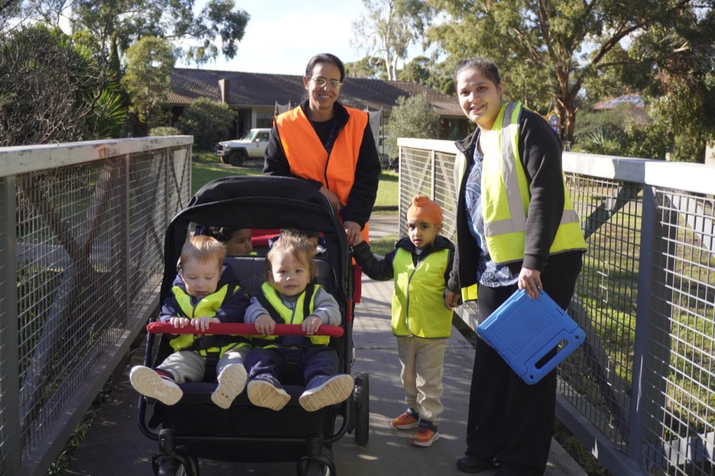 Two Billy-beet educators out walking with children in hi-vis vests