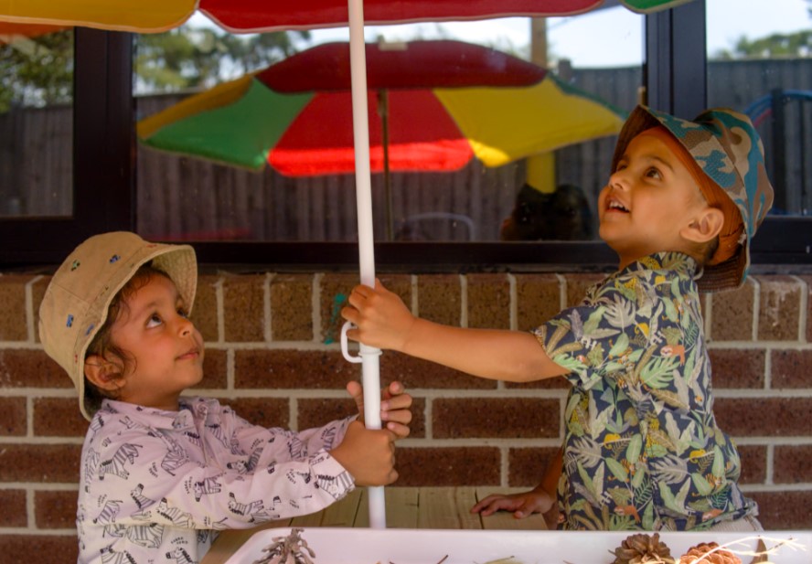 Billy-beet melton centre outdoors with two children holding up an umbrella